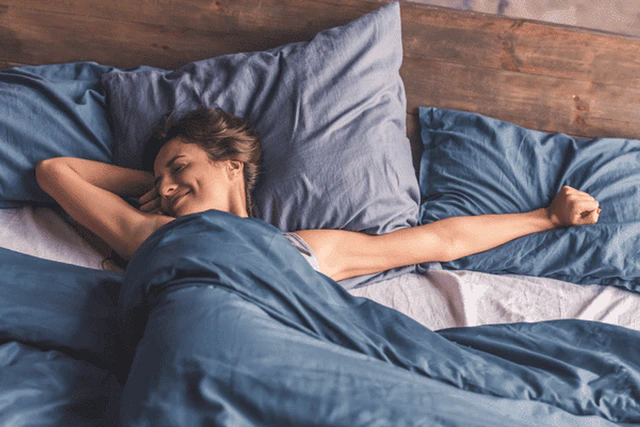 醒来后在床上舒展双臂的女性